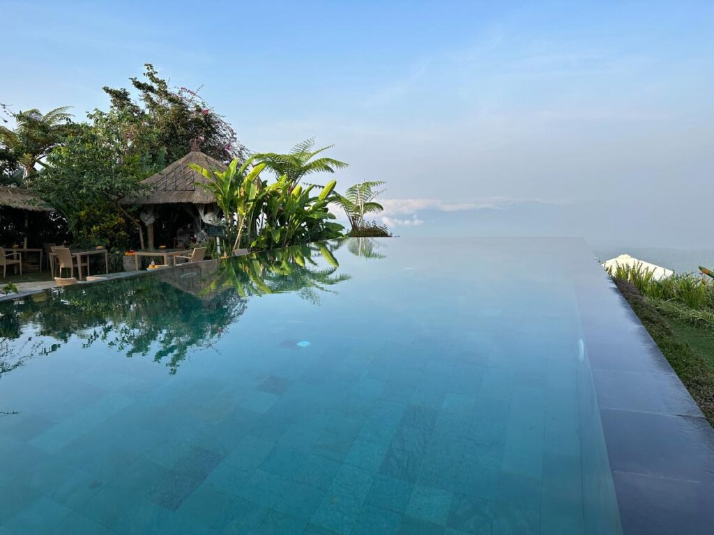 Infinity pool edge at Munduk Moding Plantation Bali appearing to merge seamlessly with the cloudy highland sky above Bali