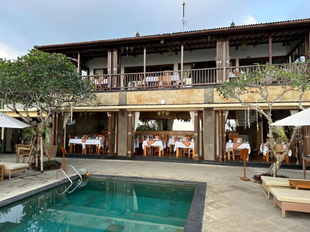 Munduk Moding Plantation Bali main building and restaurant exterior by the pool with frangipani trees and guest lounging area