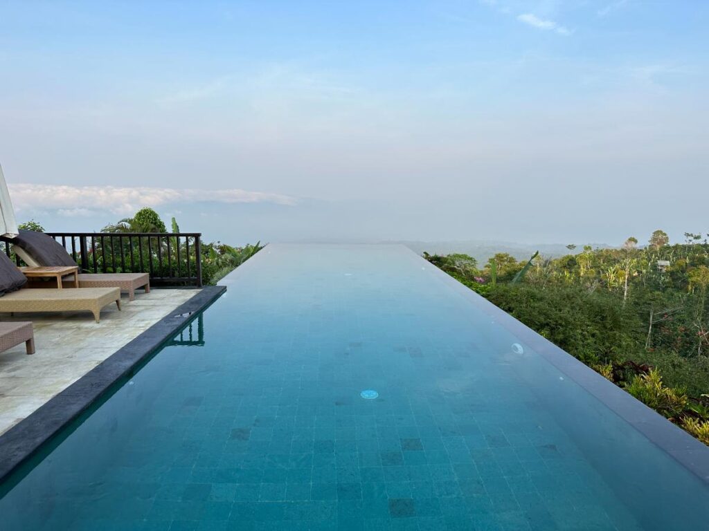 Morning view of Munduk Moding Plantation Bali main infinity pool stretching into the clear highland sky at sunrise