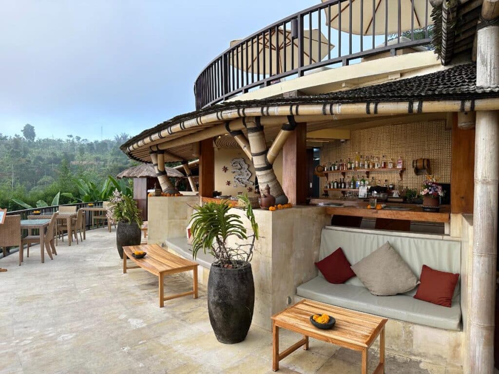 Poolside bar exterior at Munduk Moding Plantation Bali with curved stone architecture and casual lounge seating