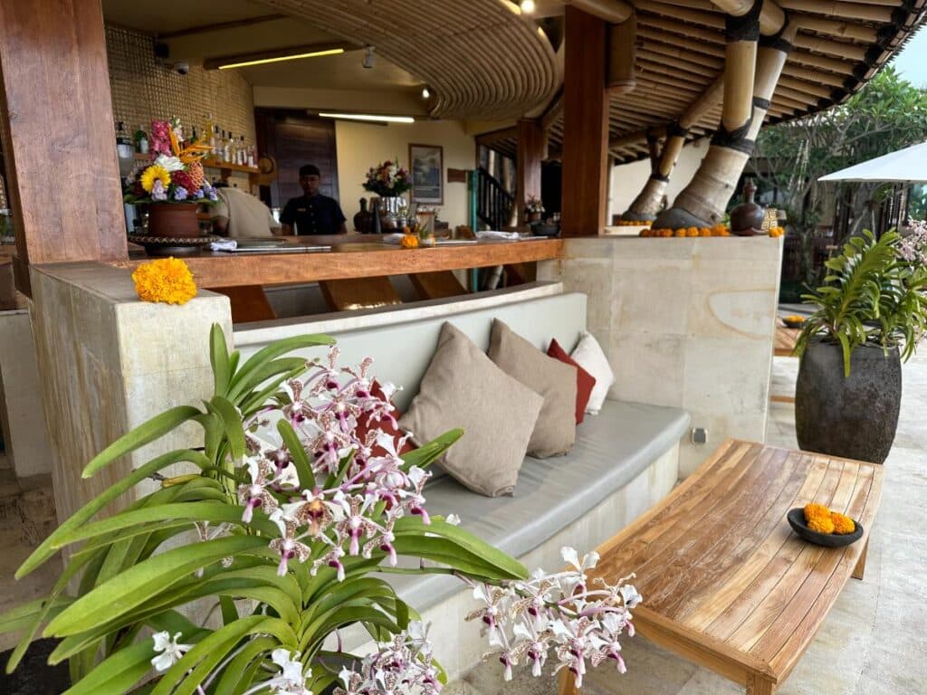 Poolside bar counter at Munduk Moding Plantation Bali decorated with fresh purple orchids and cushioned seating