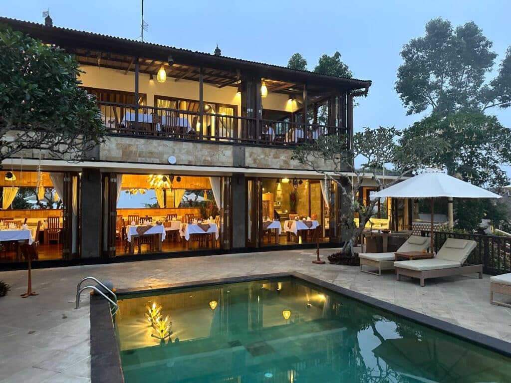 Munduk Moding Plantation Bali main building lit at night with pool terrace and restaurant visible from resort grounds