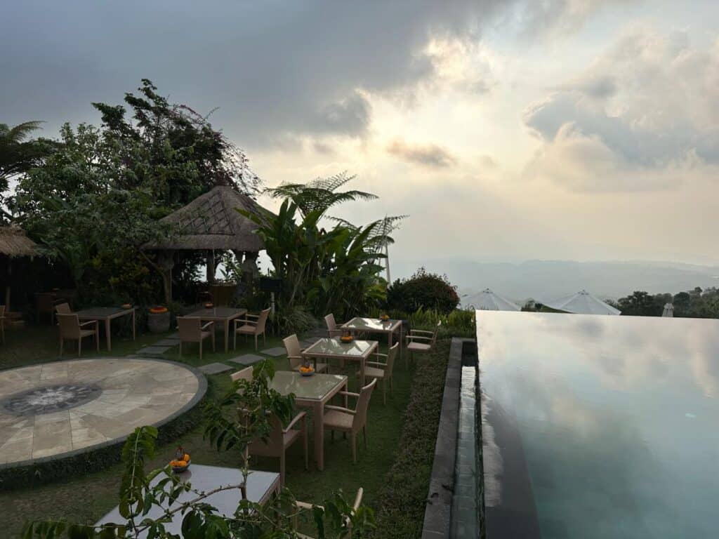 Resort grounds terrace at Munduk Moding Plantation Bali at golden hour with thatched bale pavilion and infinity pool overlook