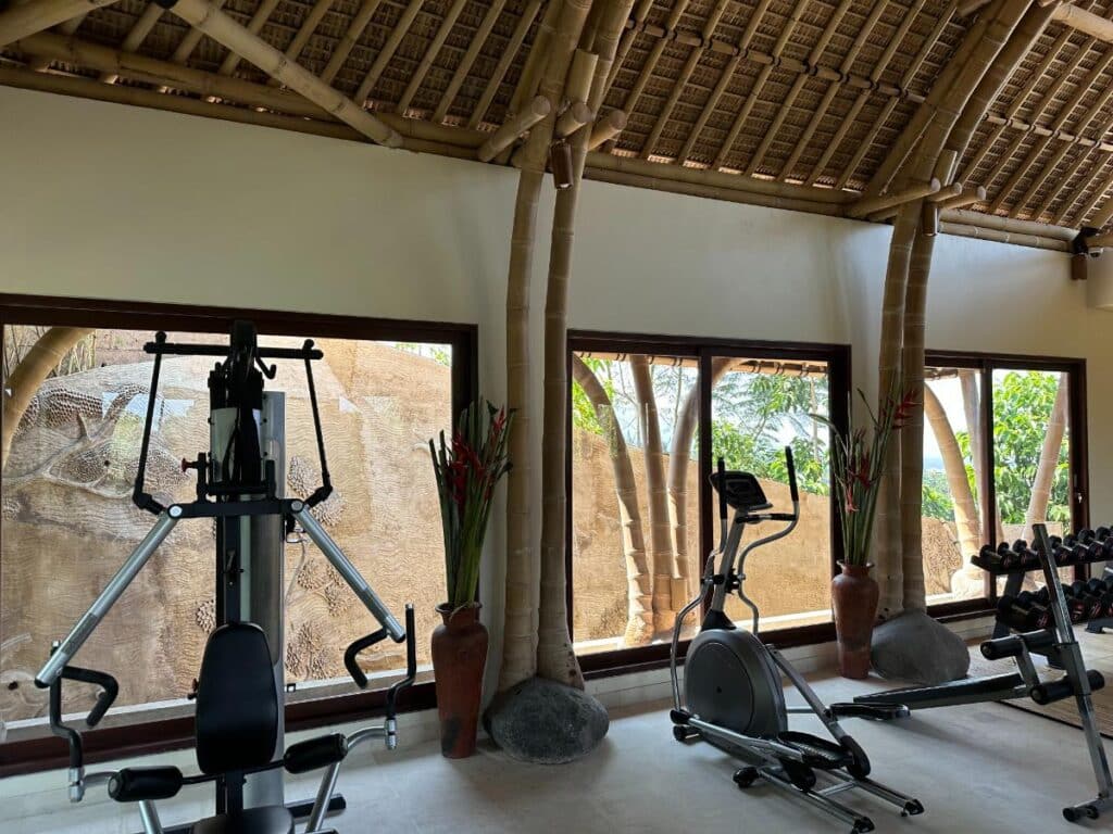 Gym interior at Munduk Moding Plantation Bali with full equipment under traditional thatched high-ceiling pavilion
