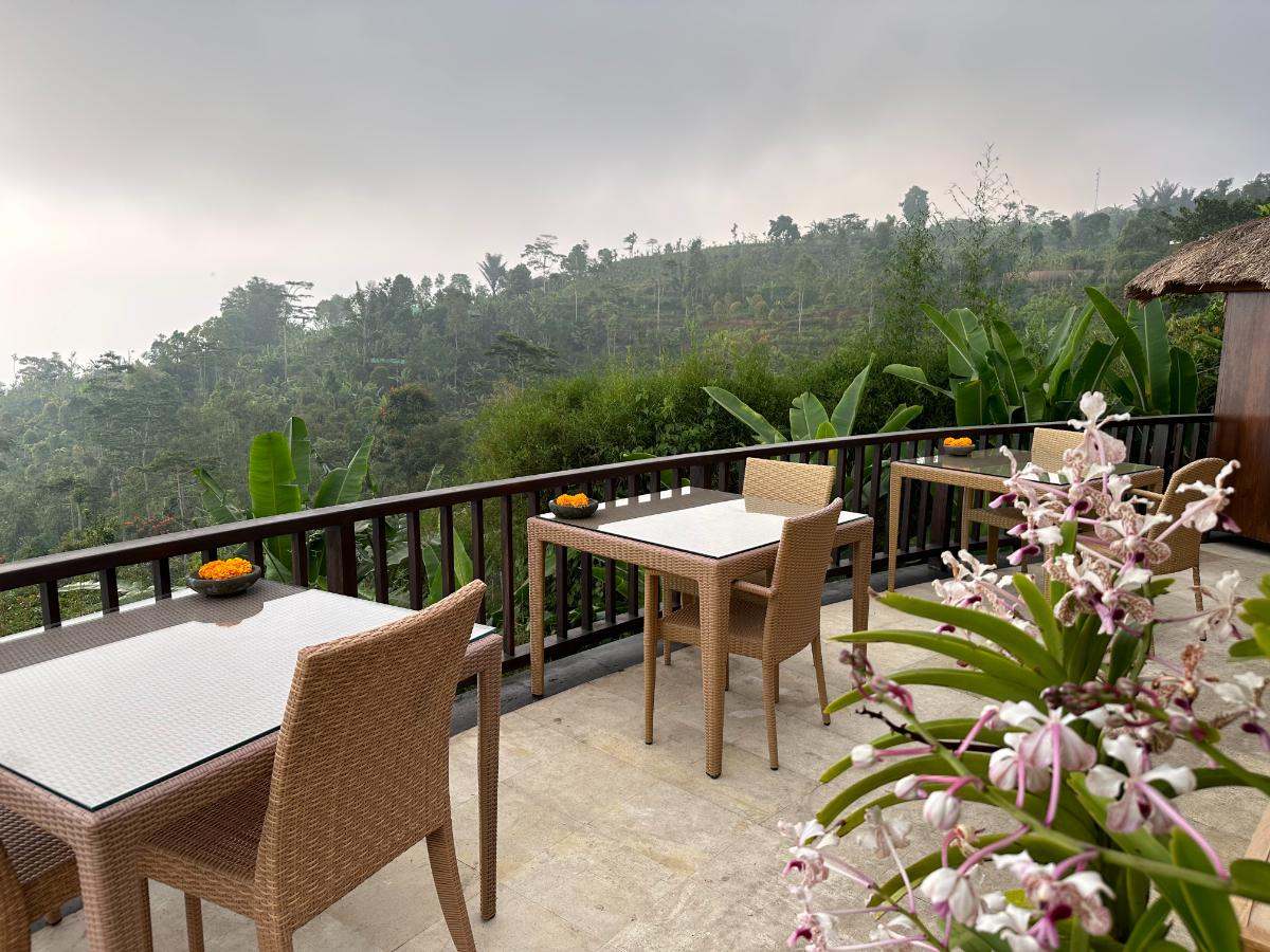 Hilltop outdoor jacuzzi at Munduk Moding Plantation Bali with guest soaking surrounded by cloudy highland landscape and wicker daybeds