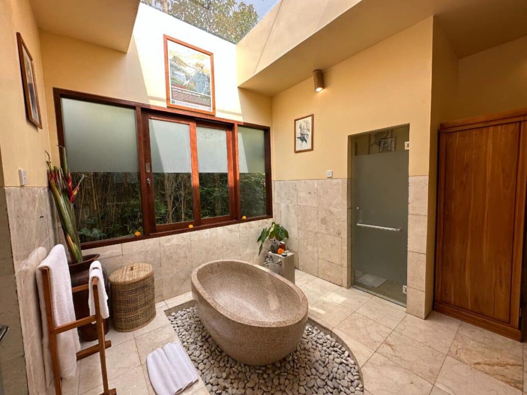 Open villa bathroom interior at Munduk Moding Plantation Bali with freestanding volcanic stone bathtub and stone tile walls