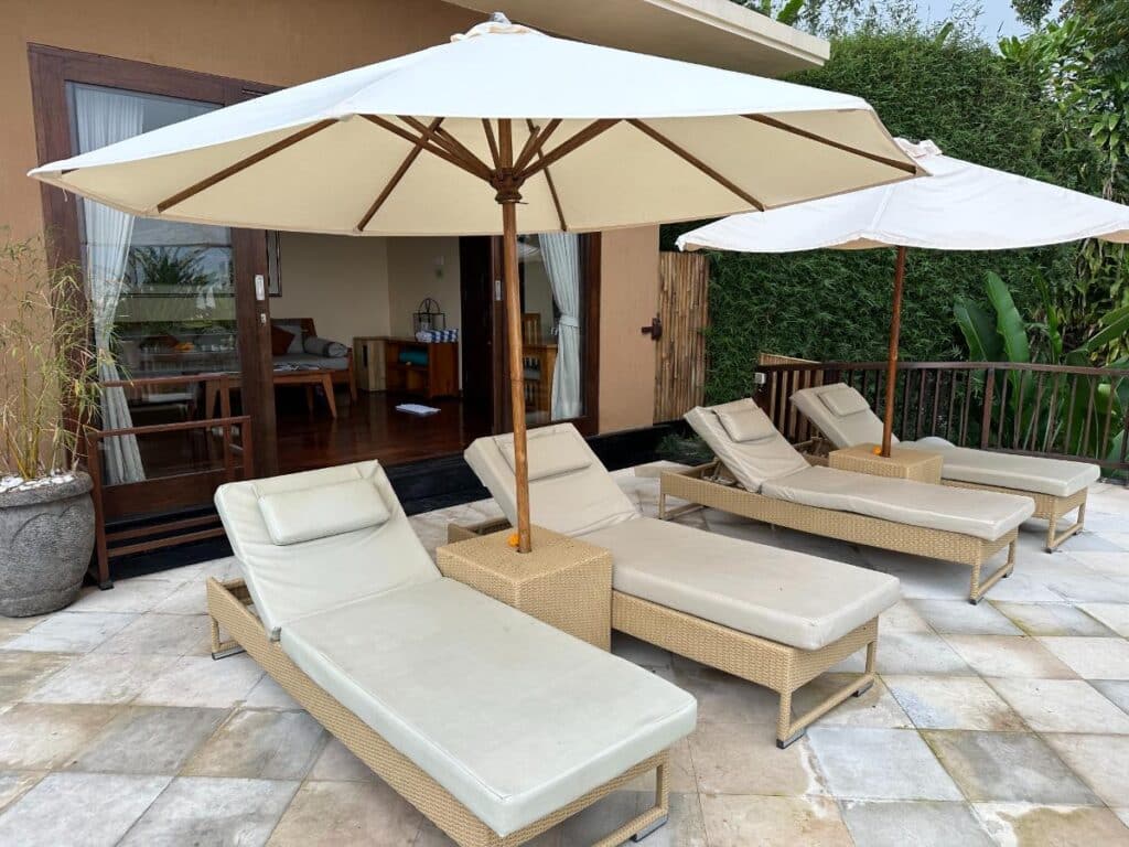Villa exterior terrace at Munduk Moding Plantation Bali with sun loungers, white parasol and tropical jungle surroundings