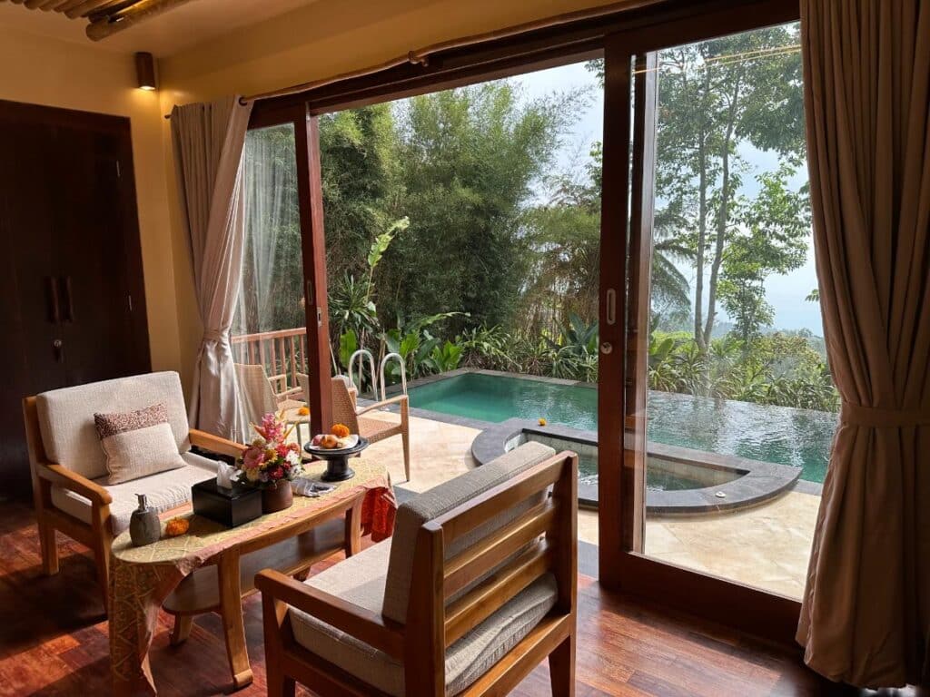 Open-plan villa living area at Munduk Moding Plantation Bali with sliding glass doors opening to private pool and misty highland view