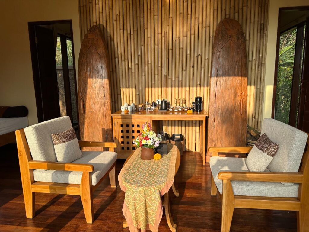 Wide-angle view of villa living room at Munduk Moding Plantation Bali with bamboo wall panelling, wooden furniture and chess set