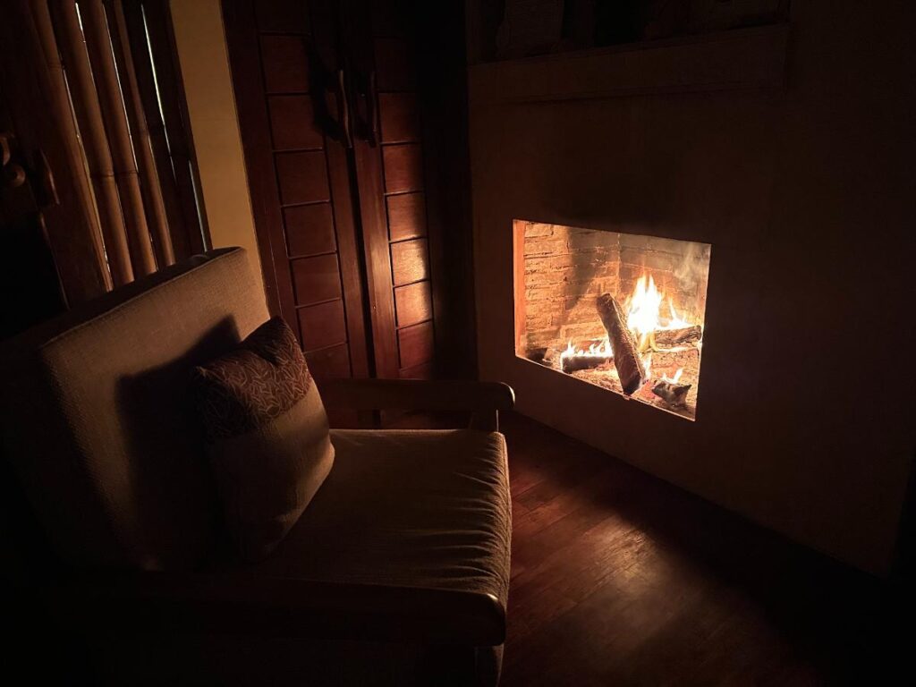Cosy villa interior at Munduk Moding Plantation Bali at night with fireplace glowing warmly in the darkened living room