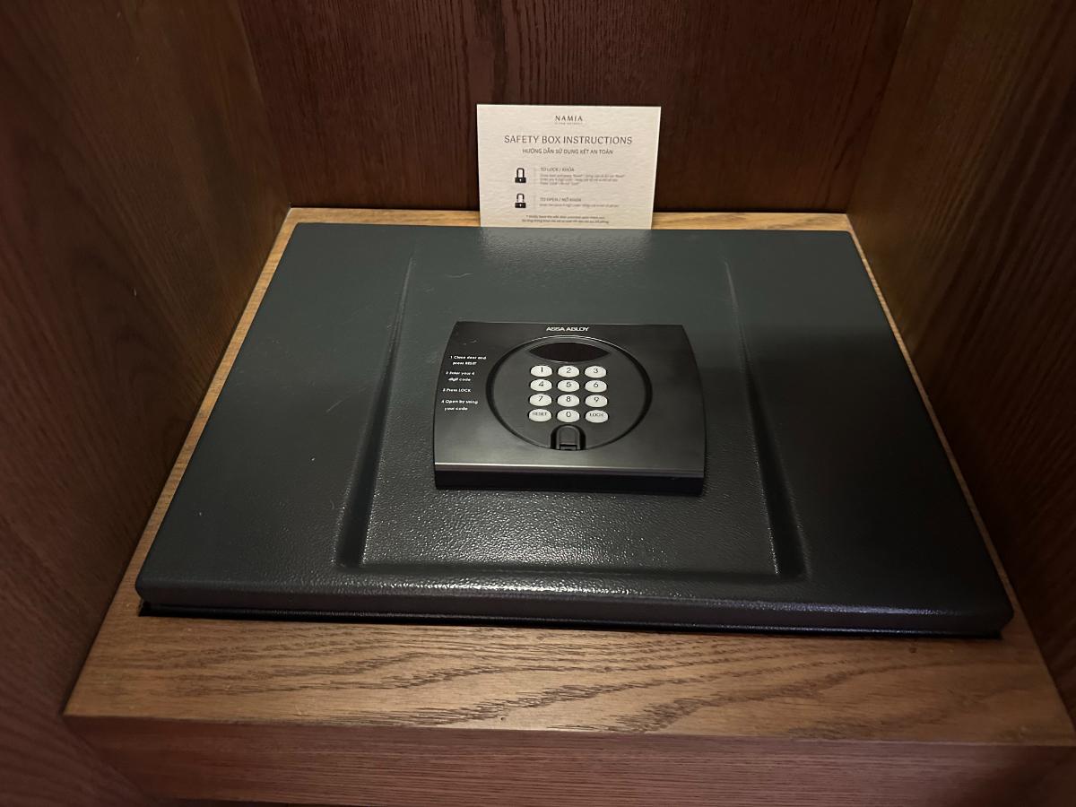 Digitaler Safe im Zimmer mit Willkommenskarte auf einem Holzregal, Namia River Retreat, Hoi An, Vietnam