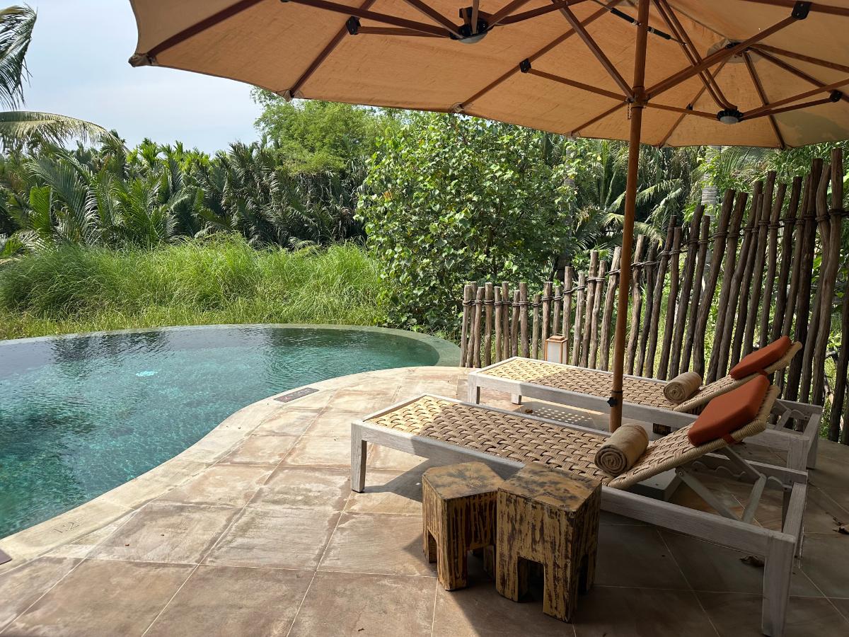 Sonnenliegen unter einem Sonnenschirm neben dem Pool der privaten Villa, Namia River Retreat, Hoi An, Vietnam