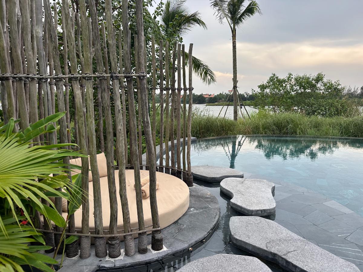 Bambusschirminsel im Hauptpool mit Blick auf den Thu Bon Fluss, Namia River Retreat, Hoi An, Vietnam