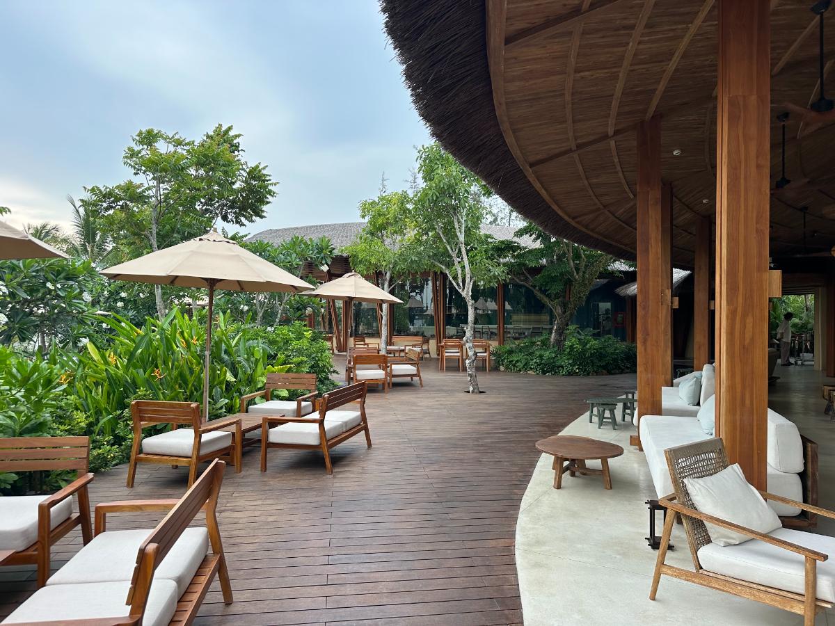 Freiluft-Holzpooldeck mit Liegestühlen unter dem Bambuspavillon-Dach, Namia River Retreat, Hoi An, Vietnam