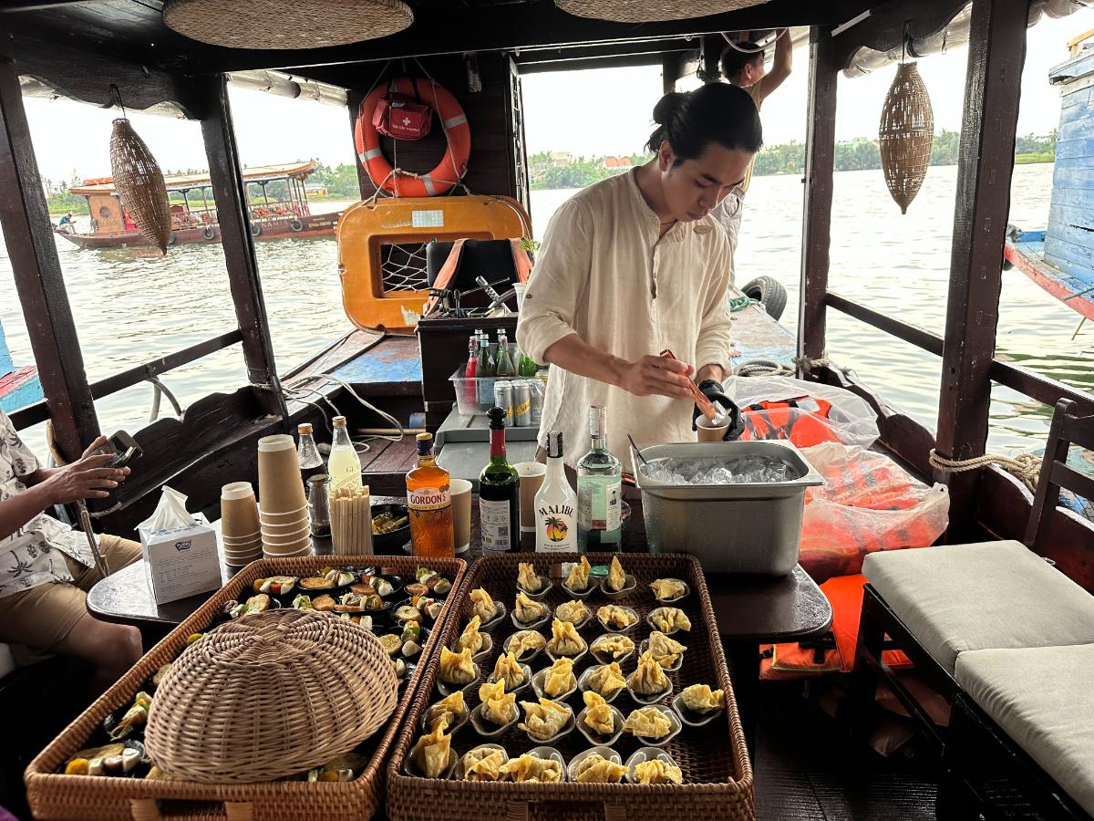 Barkeeper bei der Zubereitung von Snacks und Getränken an Bord der Namia Flusskreuzfahrt, Hoi An, Vietnam