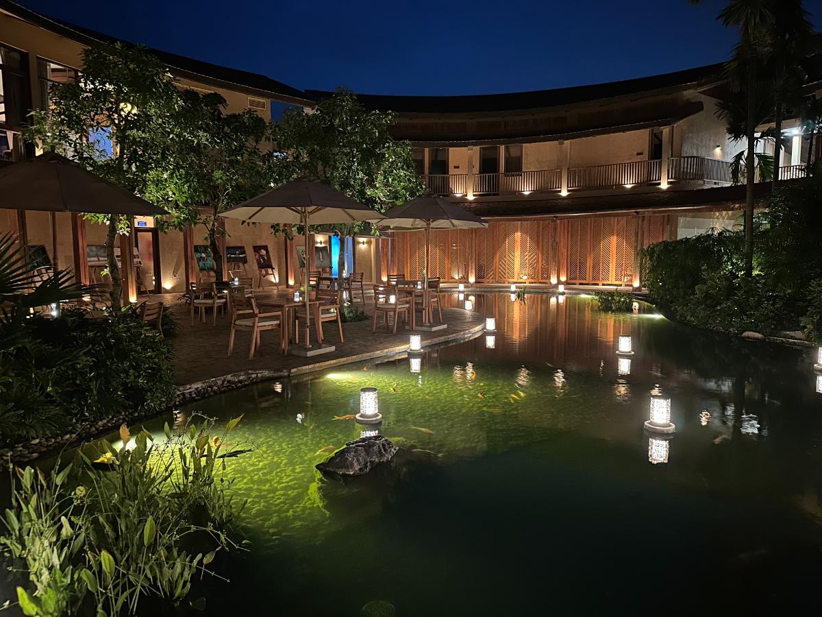 Geschwungener Restaurantpavillon mit schwimmenden Laternen auf dem Teich bei Nacht, Namia River Retreat, Hoi An, Vietnam