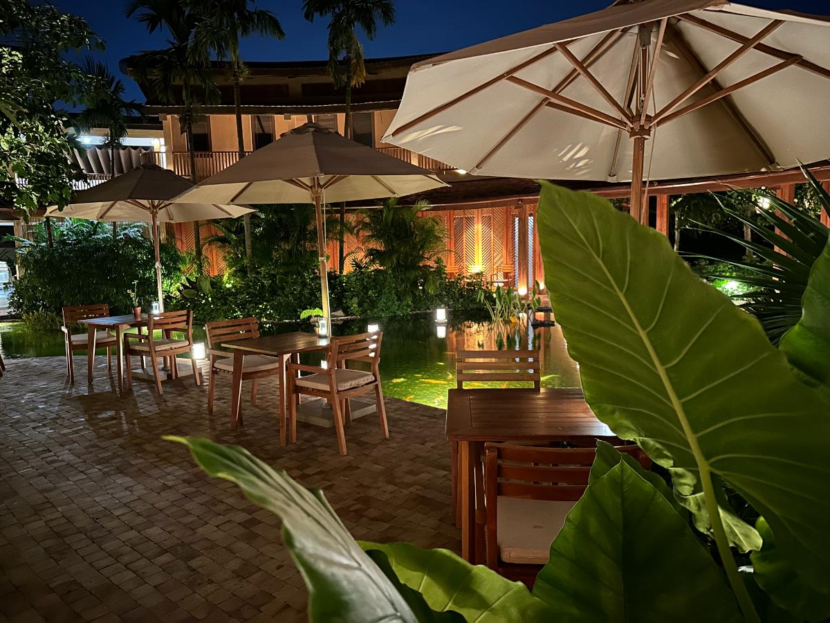 Außenterrasse des Restaurants mit Sonnenschirmen und warmer Beleuchtung bei Nacht, Namia River Retreat, Hoi An, Vietnam
