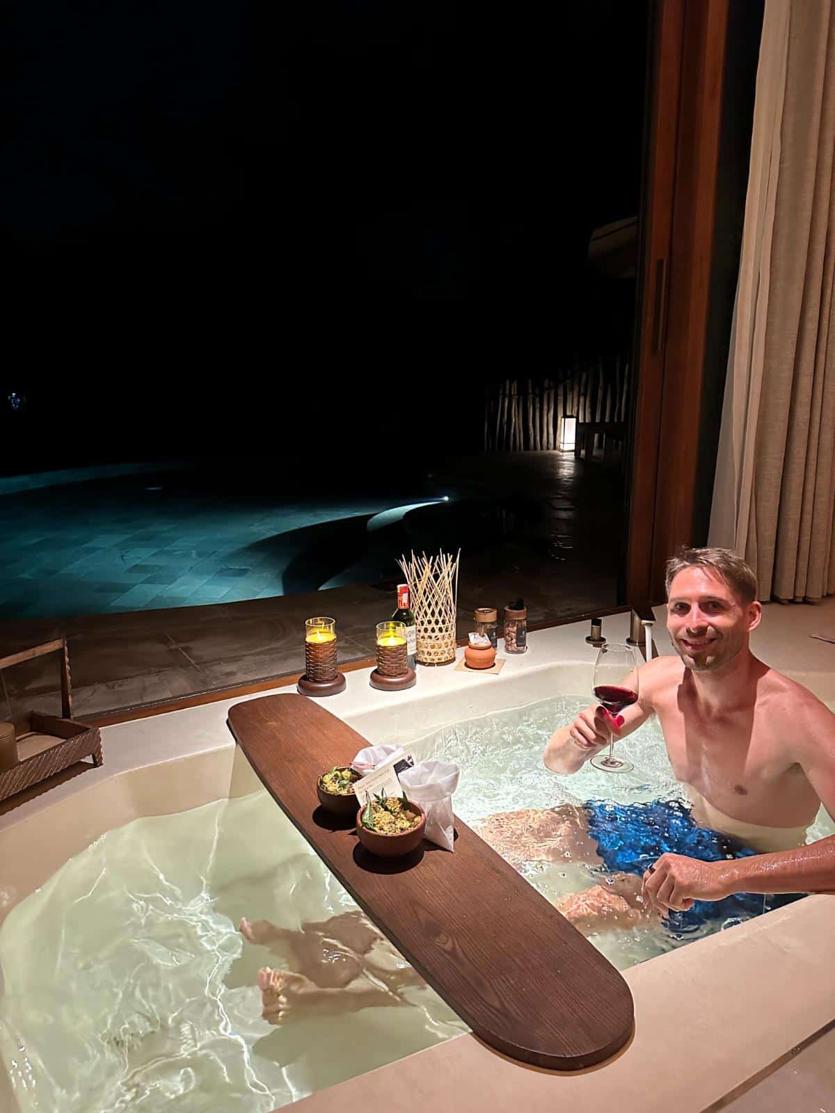 Gast mit Rotwein im kerzenbeleuchteten Außen-Whirlpool bei Nacht, Namia River Retreat Pool Villa, Hoi An, Vietnam