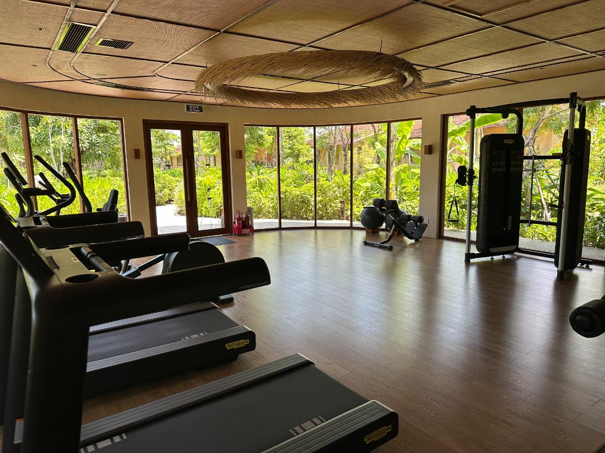 Innenraum des Fitnessstudios mit Kardiogeräten und geschwungener Bambusdecke mit Blick auf den Garten, Namia River Retreat, Hoi An, Vietnam