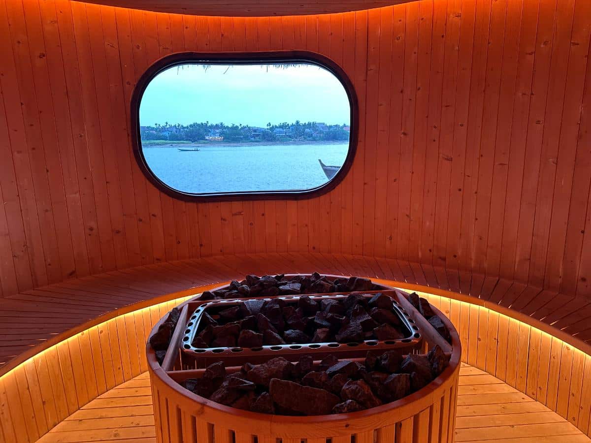 Innenraum der Sauna mit heißem Steinofen und ovalem Fenster mit Flussblick, Namia River Retreat, Hoi An, Vietnam